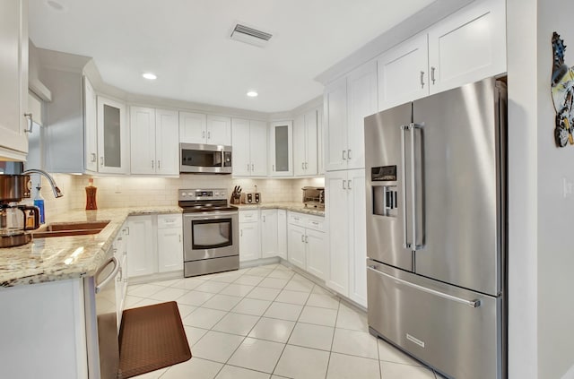 kitchen featuring white cabinets, stainless steel appliances, and light tile patterned floors