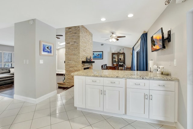 kitchen featuring light stone counters, ceiling fan, light tile patterned floors, white cabinetry, and lofted ceiling