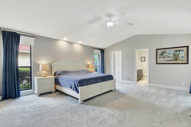 bedroom with ceiling fan, ensuite bathroom, light carpet, and lofted ceiling