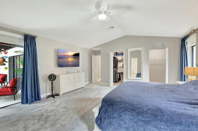 bedroom with ceiling fan, light colored carpet, vaulted ceiling, a walk in closet, and a closet