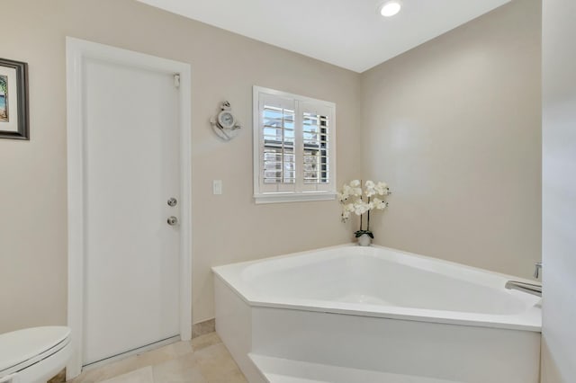 bathroom with tile patterned flooring, toilet, and a bath