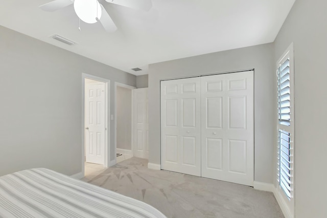 unfurnished bedroom with ceiling fan, multiple windows, light carpet, and a closet