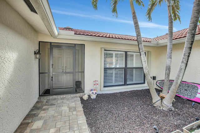 doorway to property with stucco siding and a tile roof