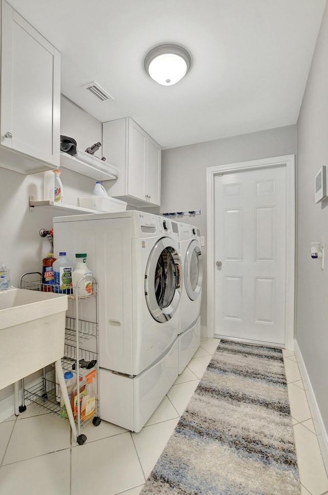 clothes washing area featuring light tile patterned flooring, cabinets, and independent washer and dryer