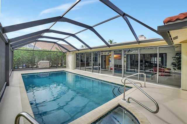 view of swimming pool featuring glass enclosure and a patio