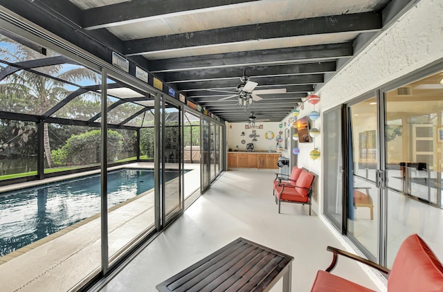 sunroom / solarium featuring ceiling fan and beam ceiling