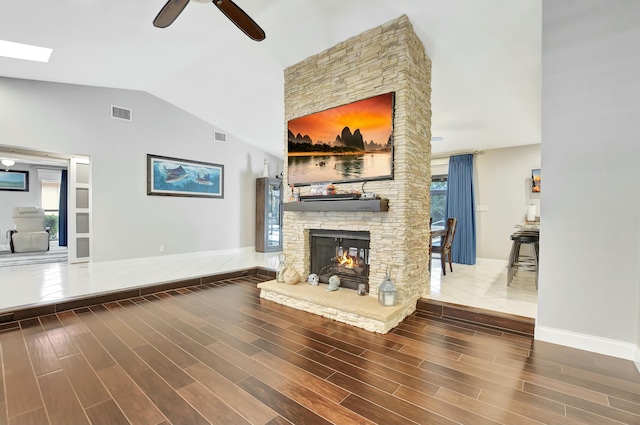 living room with a fireplace, lofted ceiling with skylight, and ceiling fan