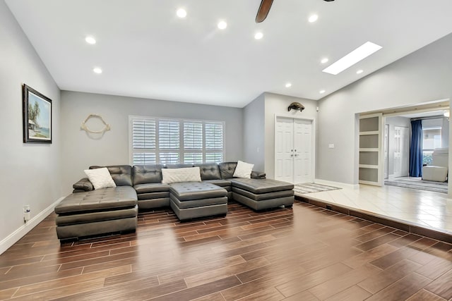 living room with ceiling fan and vaulted ceiling with skylight