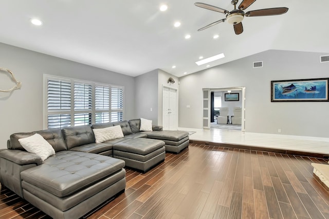 living room featuring dark hardwood / wood-style floors, ceiling fan, and vaulted ceiling with skylight