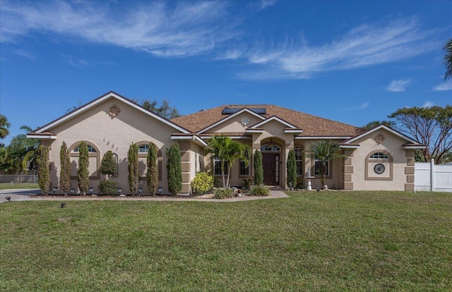 view of front of property featuring stucco siding, a front yard, and fence