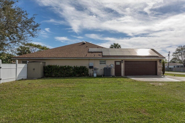 back of property featuring a garage, a yard, and solar panels