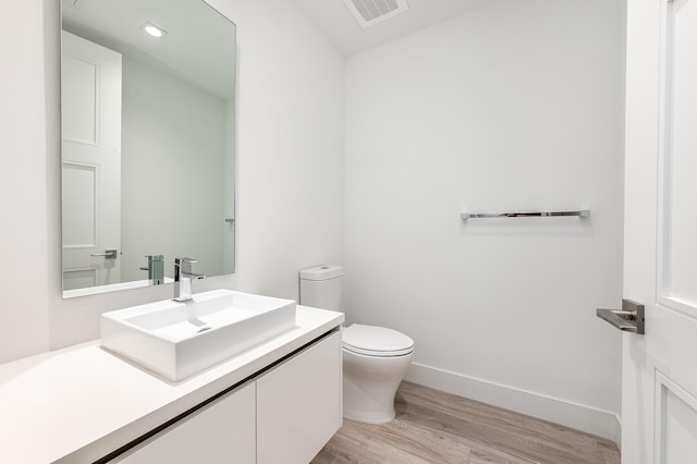 bathroom with hardwood / wood-style flooring, vanity, and toilet