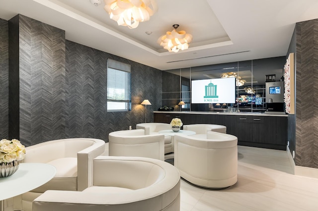 interior space with tile patterned floors, vanity, a tray ceiling, a bath, and an inviting chandelier