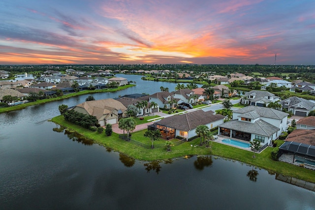 aerial view at dusk featuring a water view