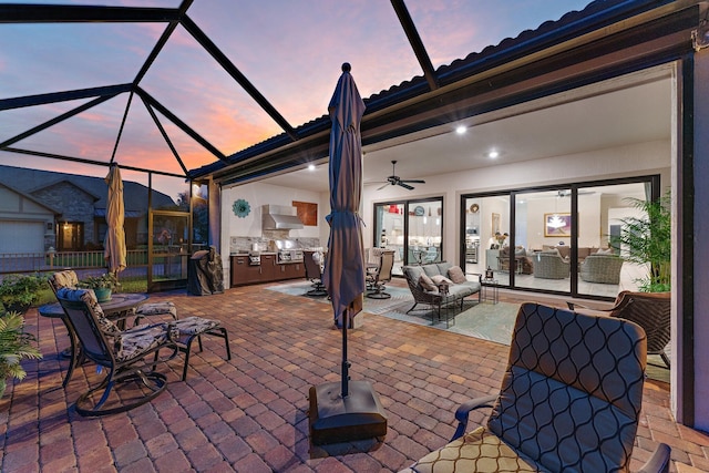 patio terrace at dusk featuring an outdoor hangout area, glass enclosure, area for grilling, and ceiling fan