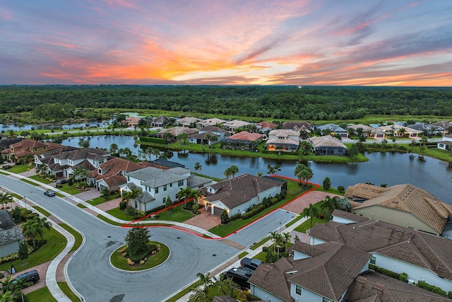 aerial view at dusk featuring a water view