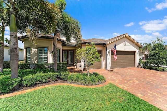 view of front facade with a garage, a front yard, and french doors