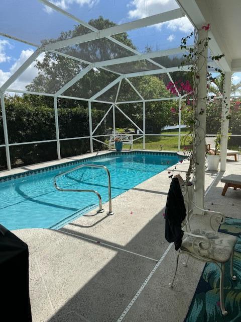 view of swimming pool featuring glass enclosure and a patio area