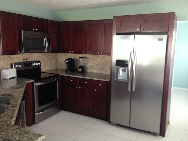 kitchen featuring decorative backsplash, light stone counters, light tile patterned floors, and stainless steel appliances