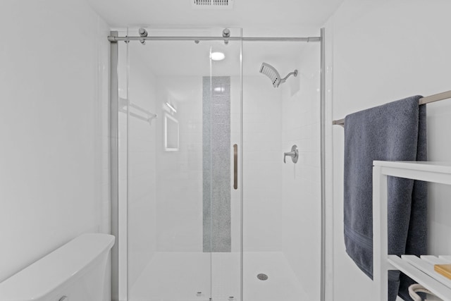 bathroom with a shower with shower door and toilet