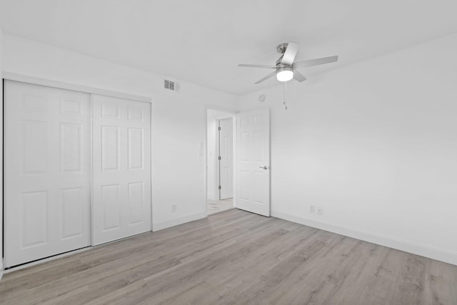 unfurnished bedroom with ceiling fan, light hardwood / wood-style flooring, and a closet