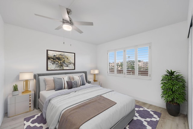 bedroom with light wood finished floors, a ceiling fan, and baseboards