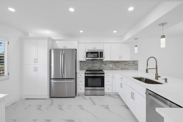 kitchen with pendant lighting, white cabinets, sink, appliances with stainless steel finishes, and tasteful backsplash