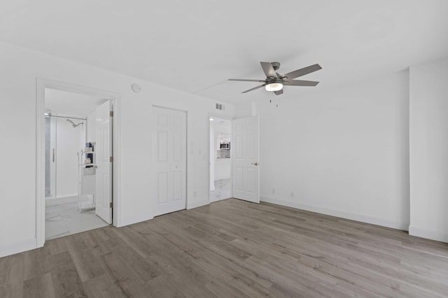 unfurnished bedroom with ensuite bathroom, ceiling fan, and light wood-type flooring