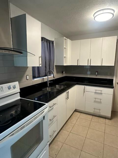 kitchen with white electric range, sink, a textured ceiling, light tile patterned floors, and white cabinets