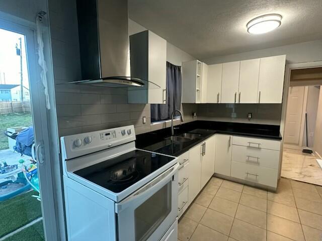 kitchen with sink, light tile patterned floors, tasteful backsplash, white cabinets, and white electric stove