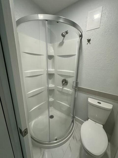 bathroom featuring a shower with door and toilet