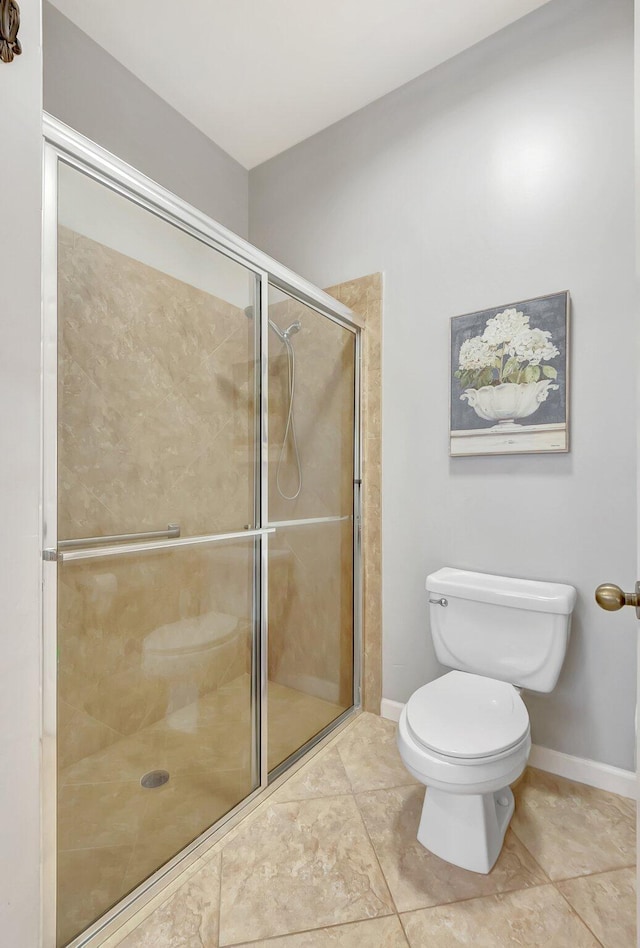 bathroom featuring tile patterned floors, toilet, and a shower with door