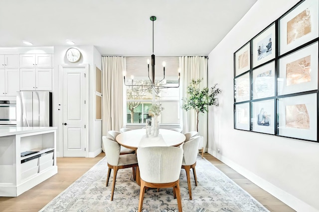 dining space with light hardwood / wood-style flooring and a chandelier