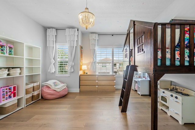 bedroom with a chandelier and light wood-type flooring