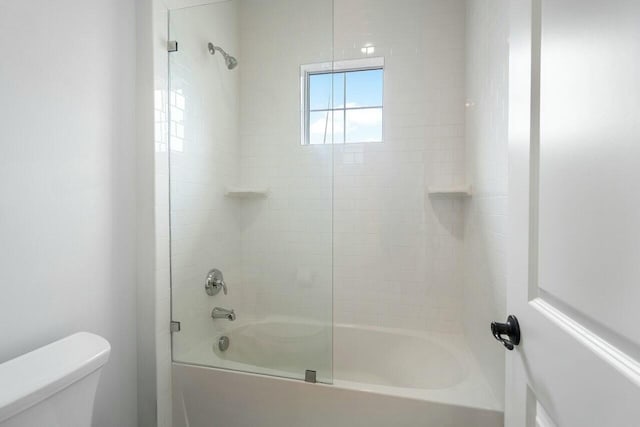 bathroom featuring toilet and tiled shower / bath