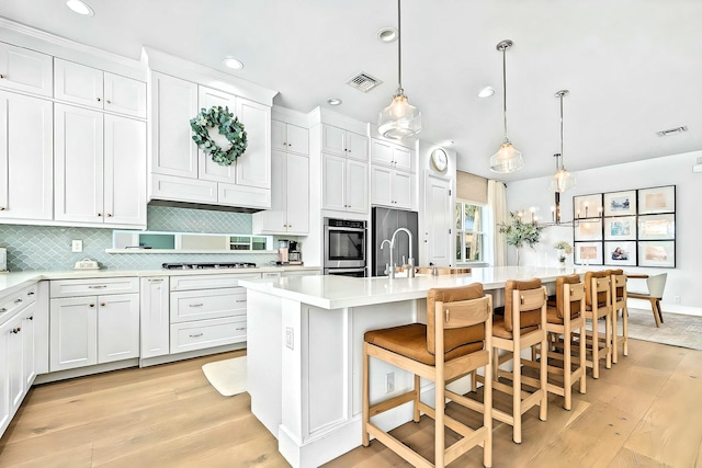 kitchen featuring pendant lighting, white cabinetry, a breakfast bar area, and an island with sink