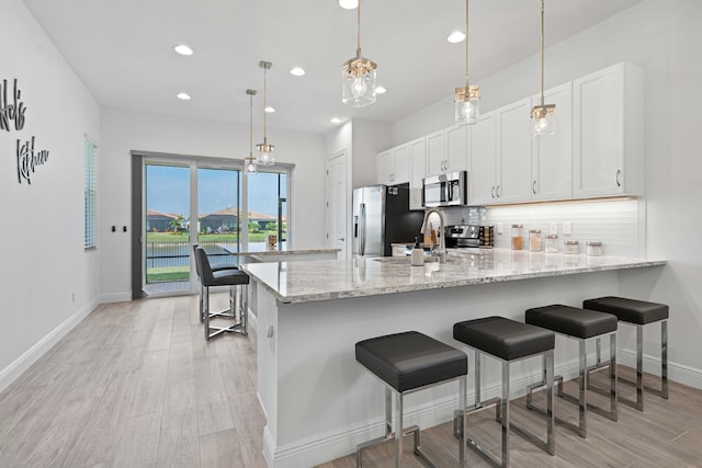 kitchen featuring kitchen peninsula, tasteful backsplash, stainless steel appliances, pendant lighting, and white cabinets