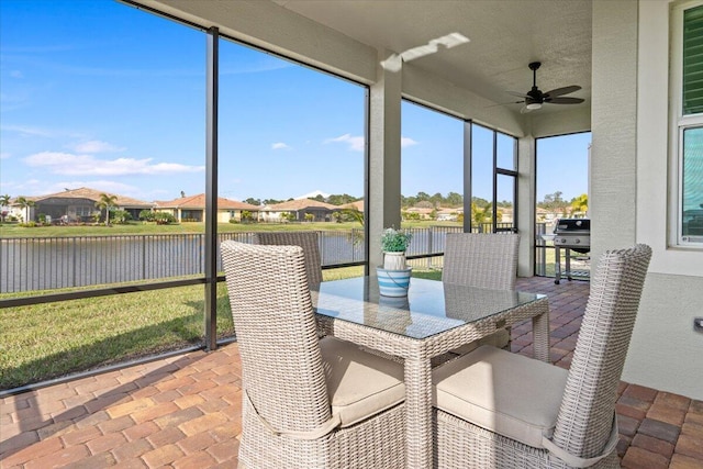 sunroom featuring a water view and ceiling fan