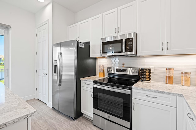 kitchen with light stone countertops, light wood-type flooring, backsplash, stainless steel appliances, and white cabinetry