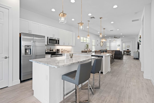 kitchen featuring kitchen peninsula, appliances with stainless steel finishes, a breakfast bar, ceiling fan, and hanging light fixtures