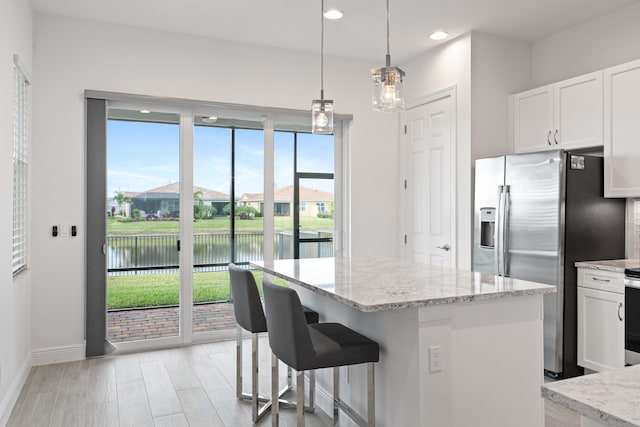 kitchen with pendant lighting, a center island, white cabinets, a water view, and stainless steel refrigerator with ice dispenser