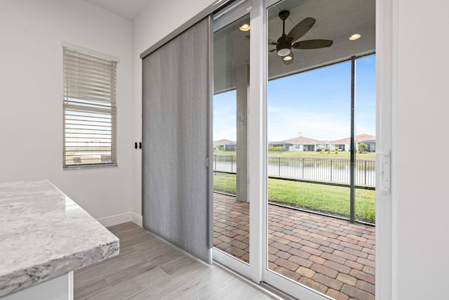 entryway with ceiling fan, light hardwood / wood-style flooring, and a water view