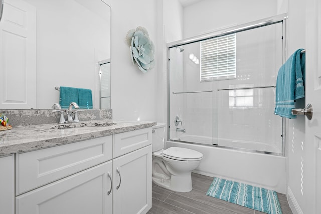 full bathroom featuring vanity, toilet, and combined bath / shower with glass door