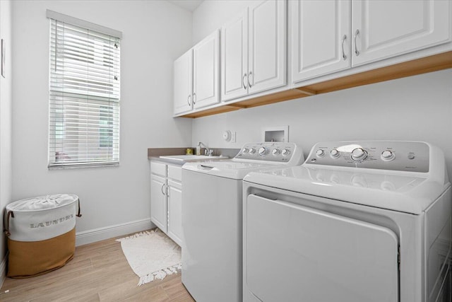 washroom featuring washer and dryer, cabinets, sink, and a wealth of natural light