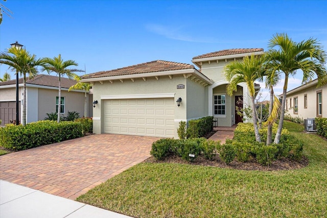 mediterranean / spanish home featuring a front lawn, a garage, and central AC unit