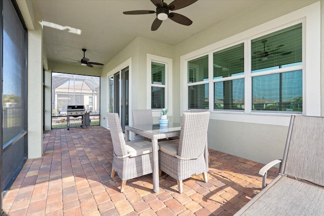 view of patio with ceiling fan and glass enclosure