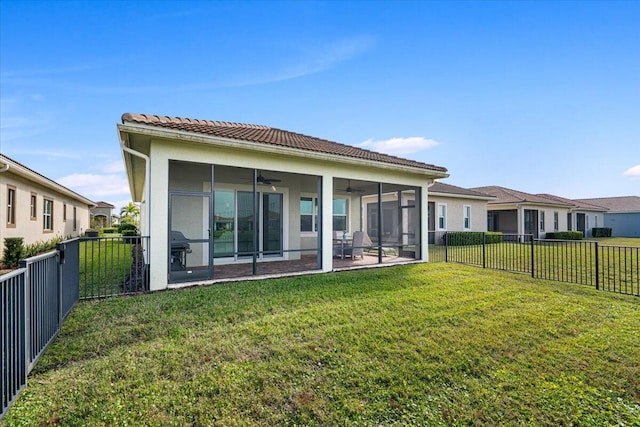 back of property with a sunroom, ceiling fan, and a yard