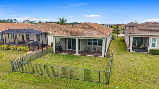 back of property with glass enclosure and a lawn