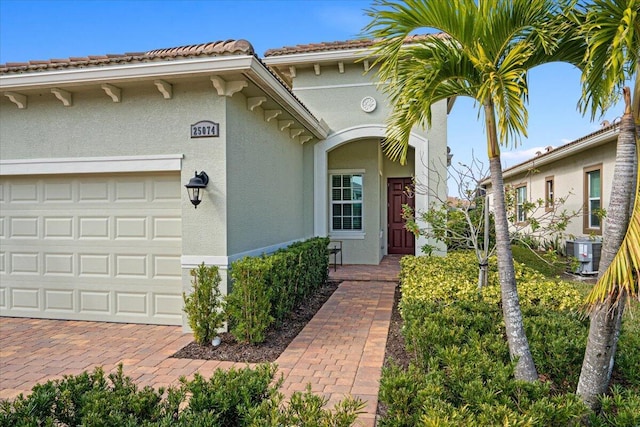 view of exterior entry featuring cooling unit and a garage