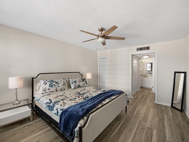 bedroom with ceiling fan, a textured ceiling, baseboards, and wood finished floors